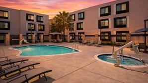 A hotel with a pool, lounge chairs, and a sunset sky. - Hampton Inn & Suites by Hilton San Diego SeaWorld Near Old Town (San Diego)