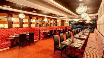 A restaurant with red cushioned booths, black chairs, and tables set for dining.