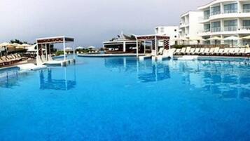 Alberca al aire libre, sombrillas en la alberca y camastros