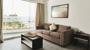 A living room with a sofa, a coffee table, a small desk, and a painting on the wall.