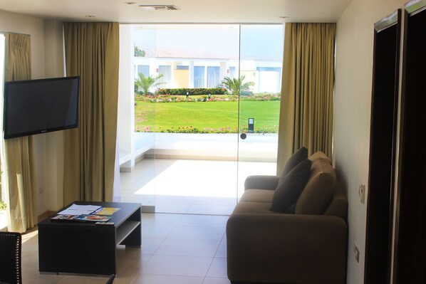 Una sala de estar con televisión de pantalla plana, un sofá y una mesa de centro.