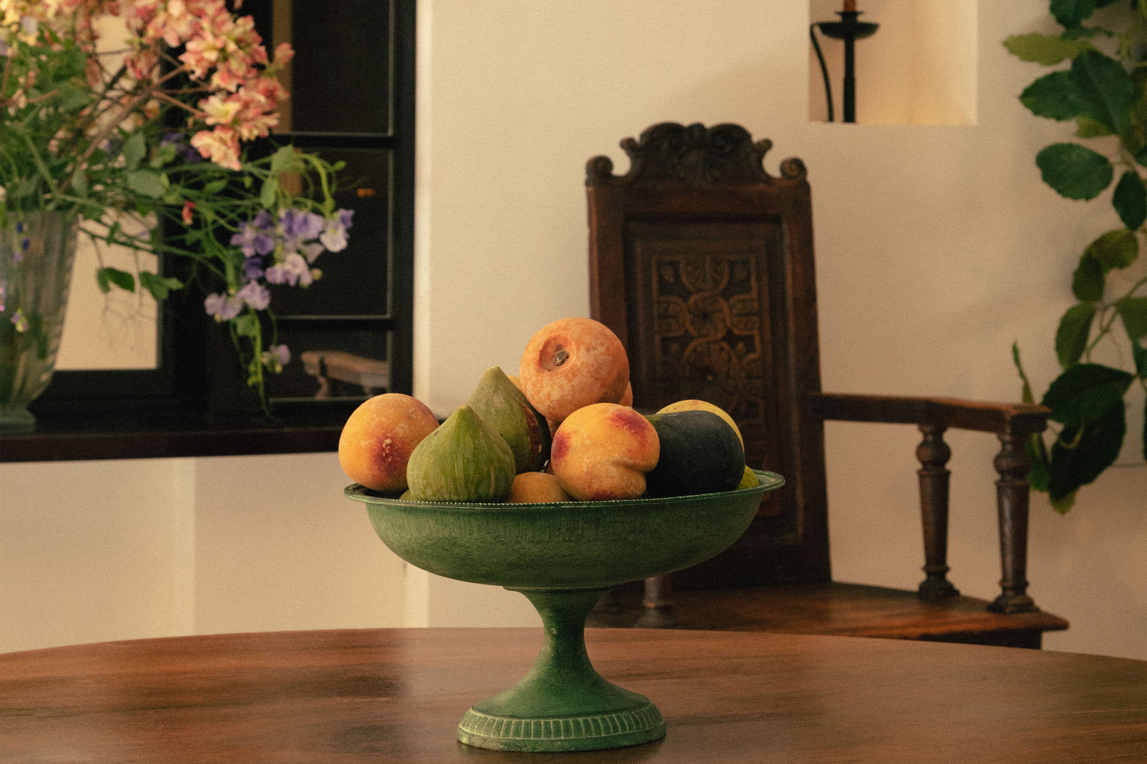 A green bowl filled with fruits on a wooden table.