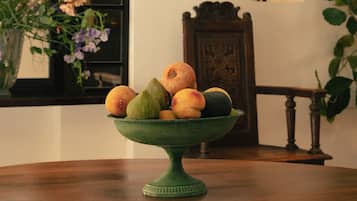 Un saladier vert rempli de fruits, posé sur une table en bois.