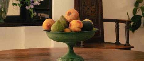 A green bowl filled with fruits on a wooden table.