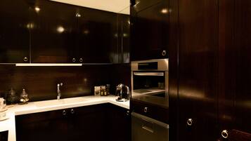 A modern kitchen with dark wood cabinets, stainless steel appliances, and a white countertop.