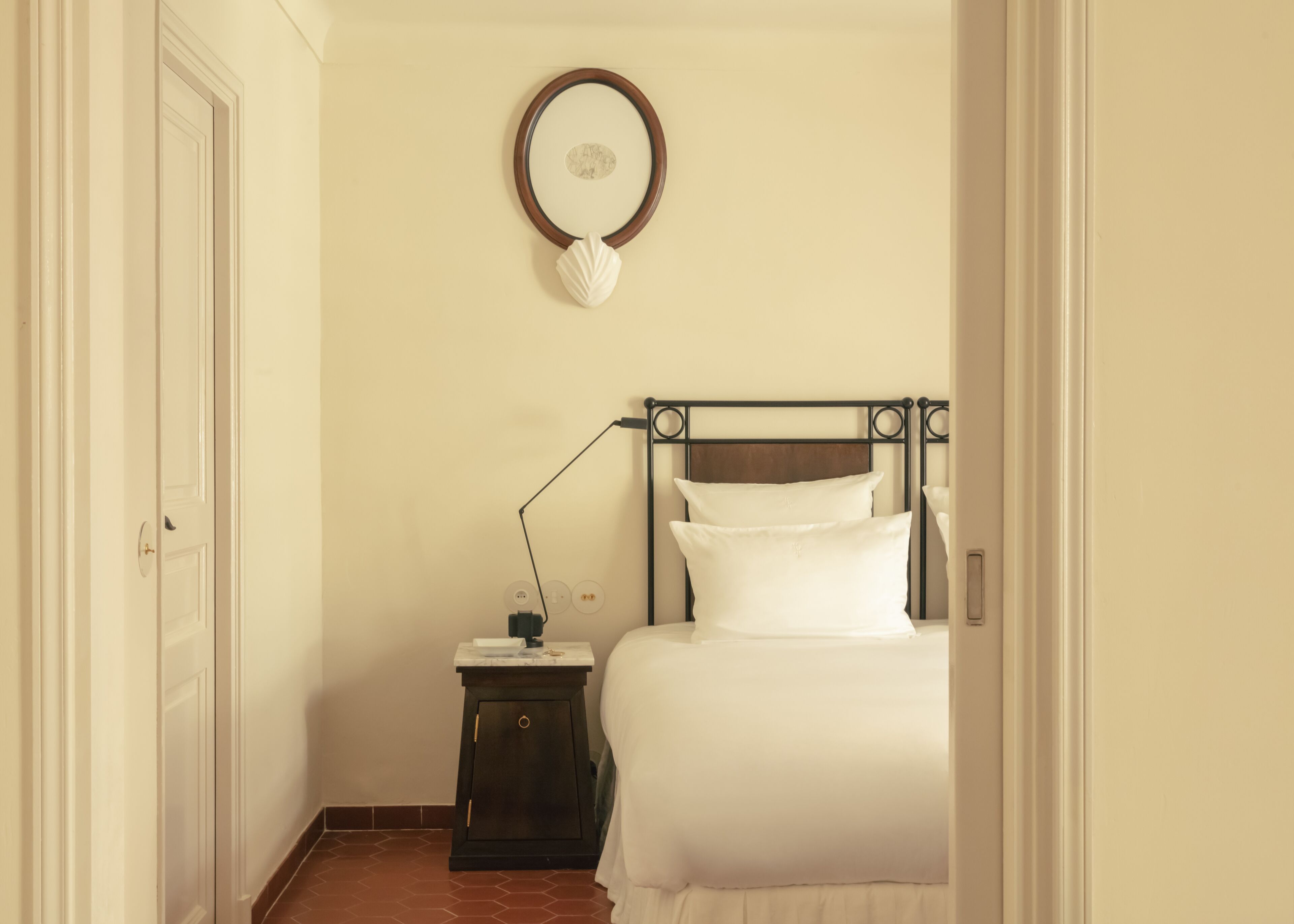 Une chambre à coucher comprenant un lit, une table de chevet, une lampe et un miroir fixé au mur.