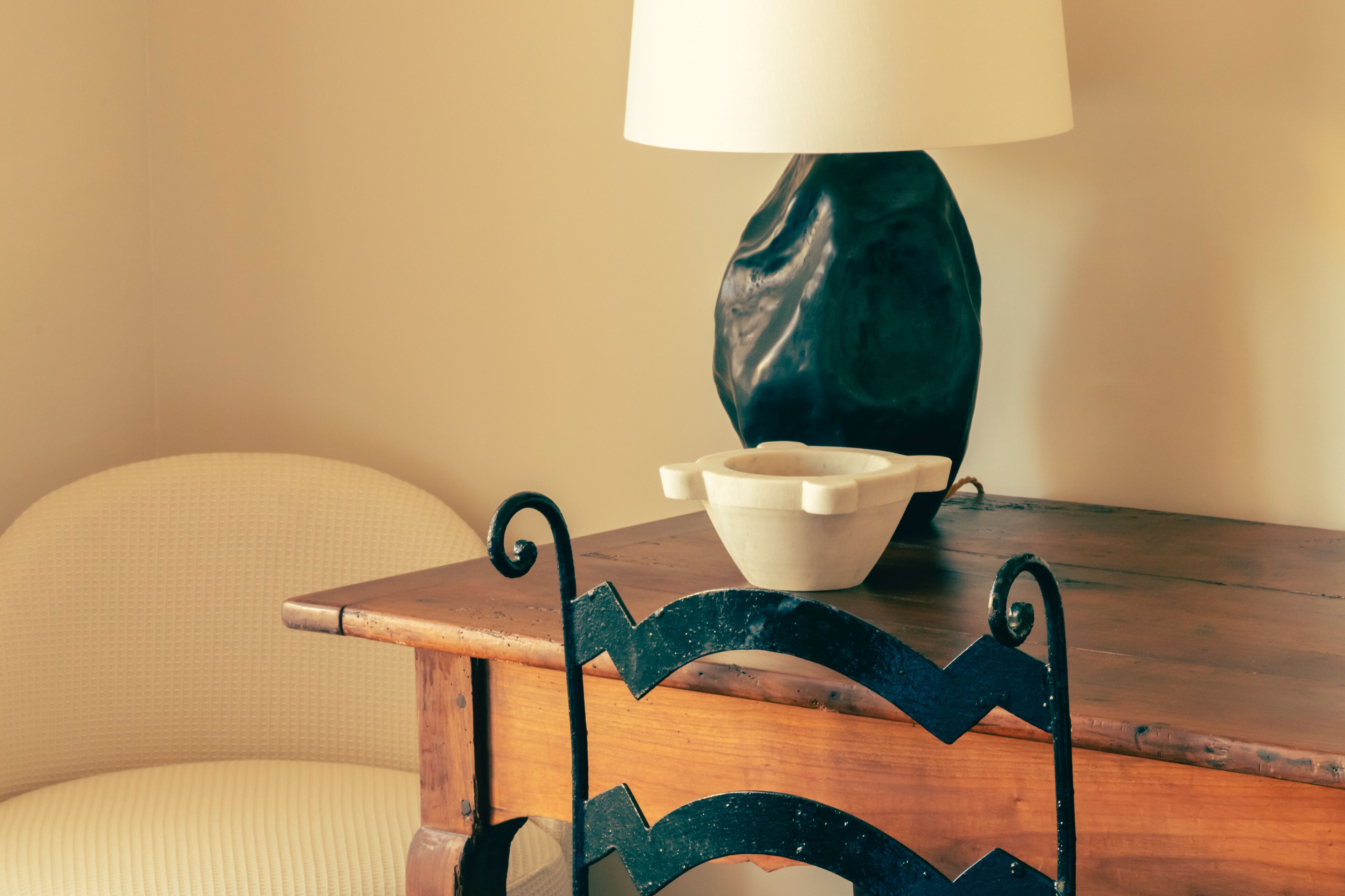 A wooden table with a white bowl and a dark green lamp.