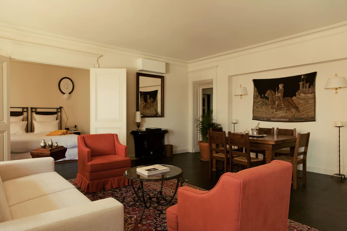 Una sala de estar con sofá, sillón y zona de comedor con mesa y sillas.