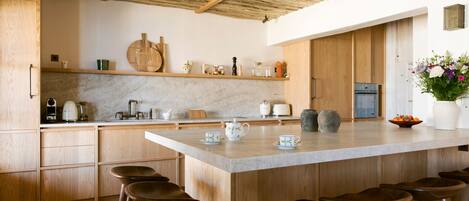 Una cocina moderna con una isla grande, taburetes de madera y una variedad de utensilios de cocina y elementos decorativos.