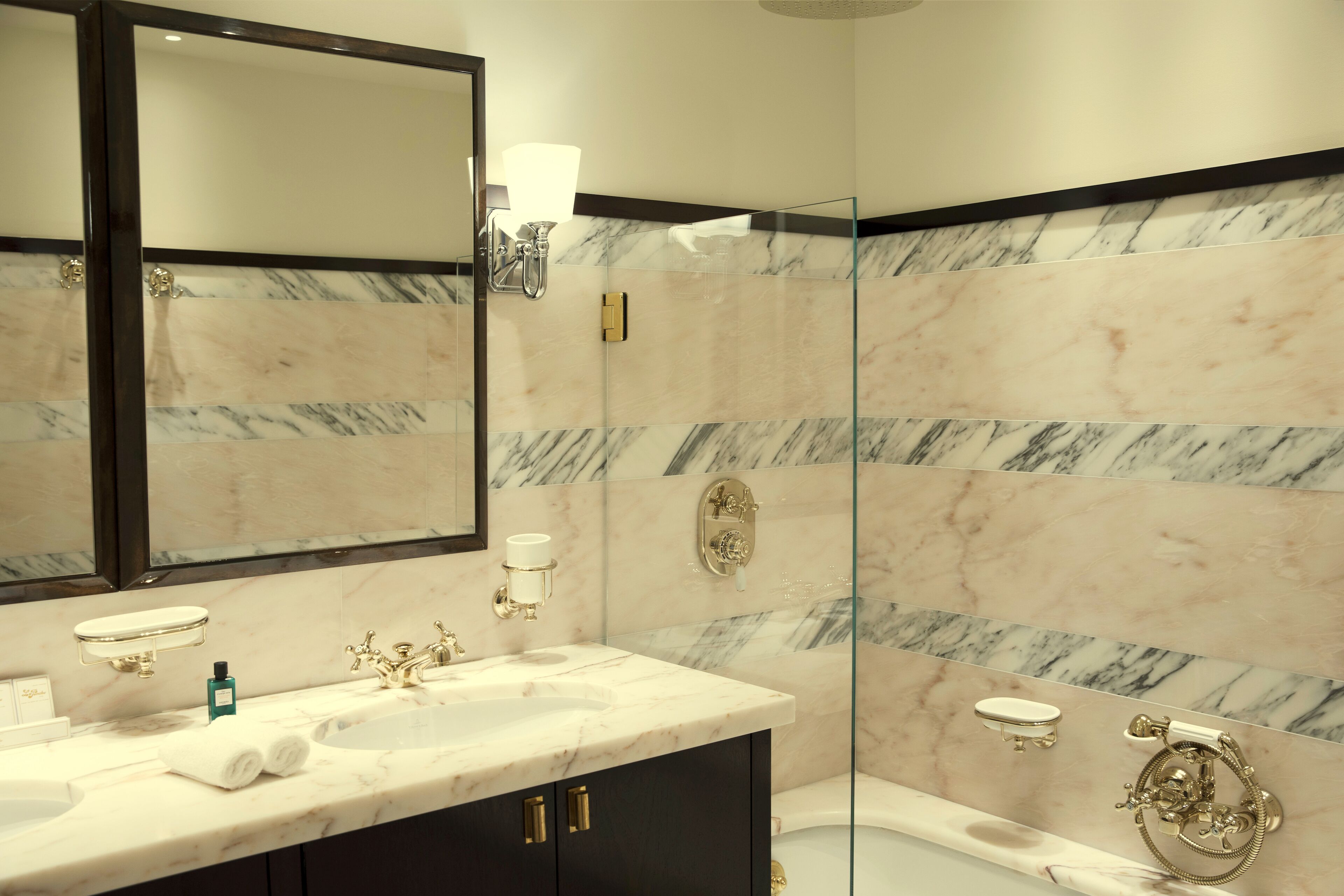 A bathroom with a marble vanity, a large mirror, a glass shower enclosure, and a toilet with a bidet.