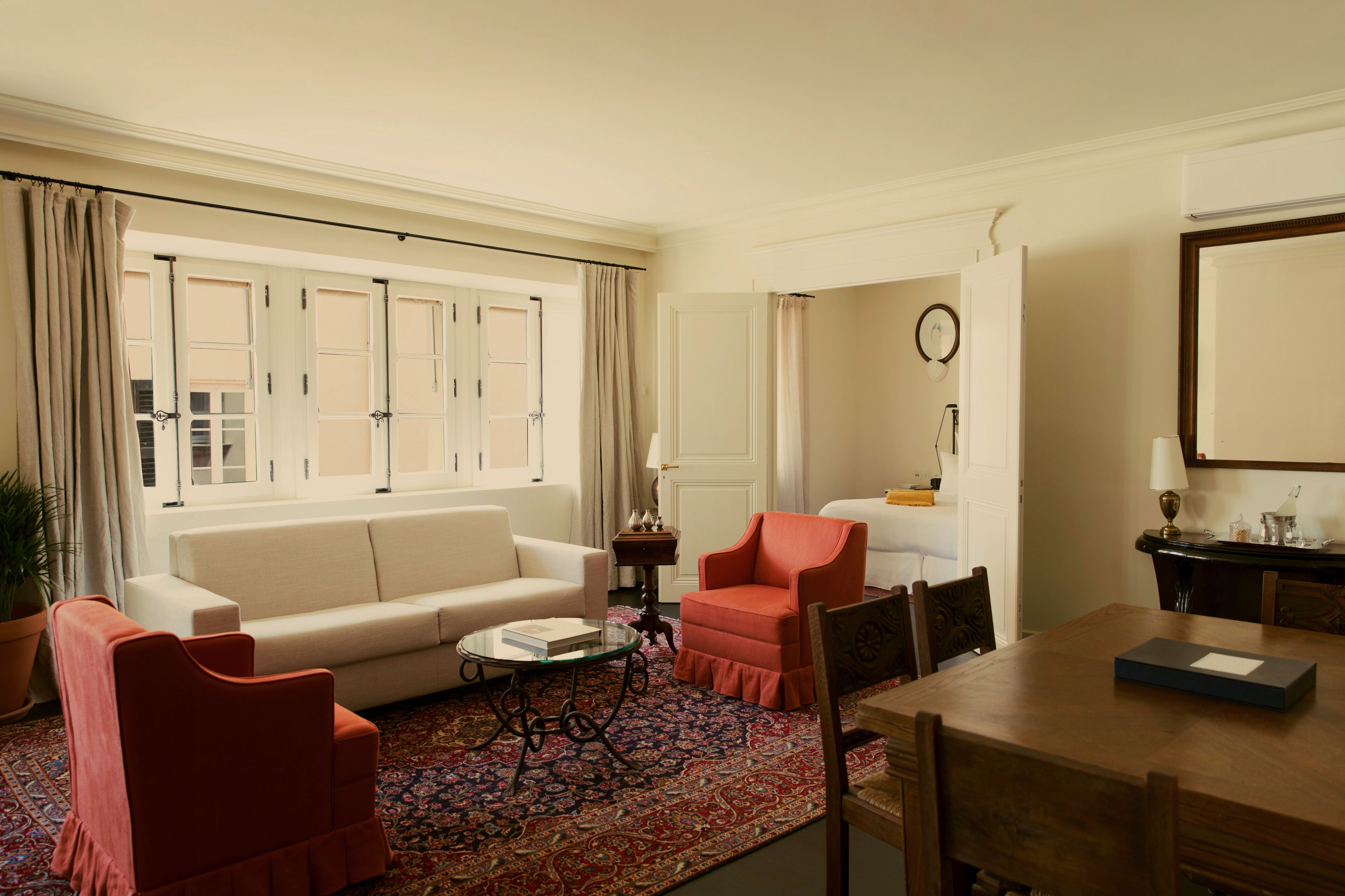 Un salon comprenant un canapé, deux fauteuils, une table basse et une table à manger.