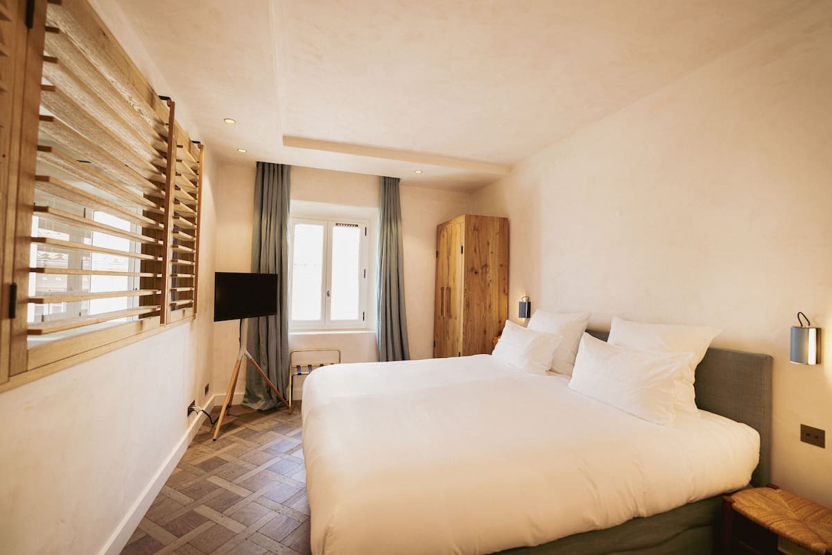 Un dormitorio con una cama grande, un armario de madera, un escritorio y una ventana con persianas.
