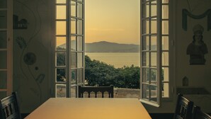 A room with a large window opening to a view of the sea and hills. - Hôtel La Ponche (Saint-Tropez)