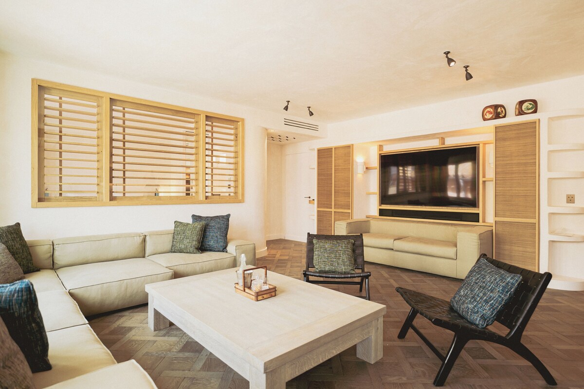 A living room with a sectional sofa, a coffee table, a TV, and a fireplace.