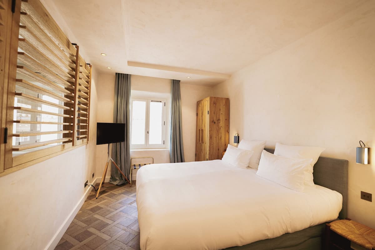 Un dormitorio con una cama grande, un armario de madera, un escritorio y una ventana con persianas.