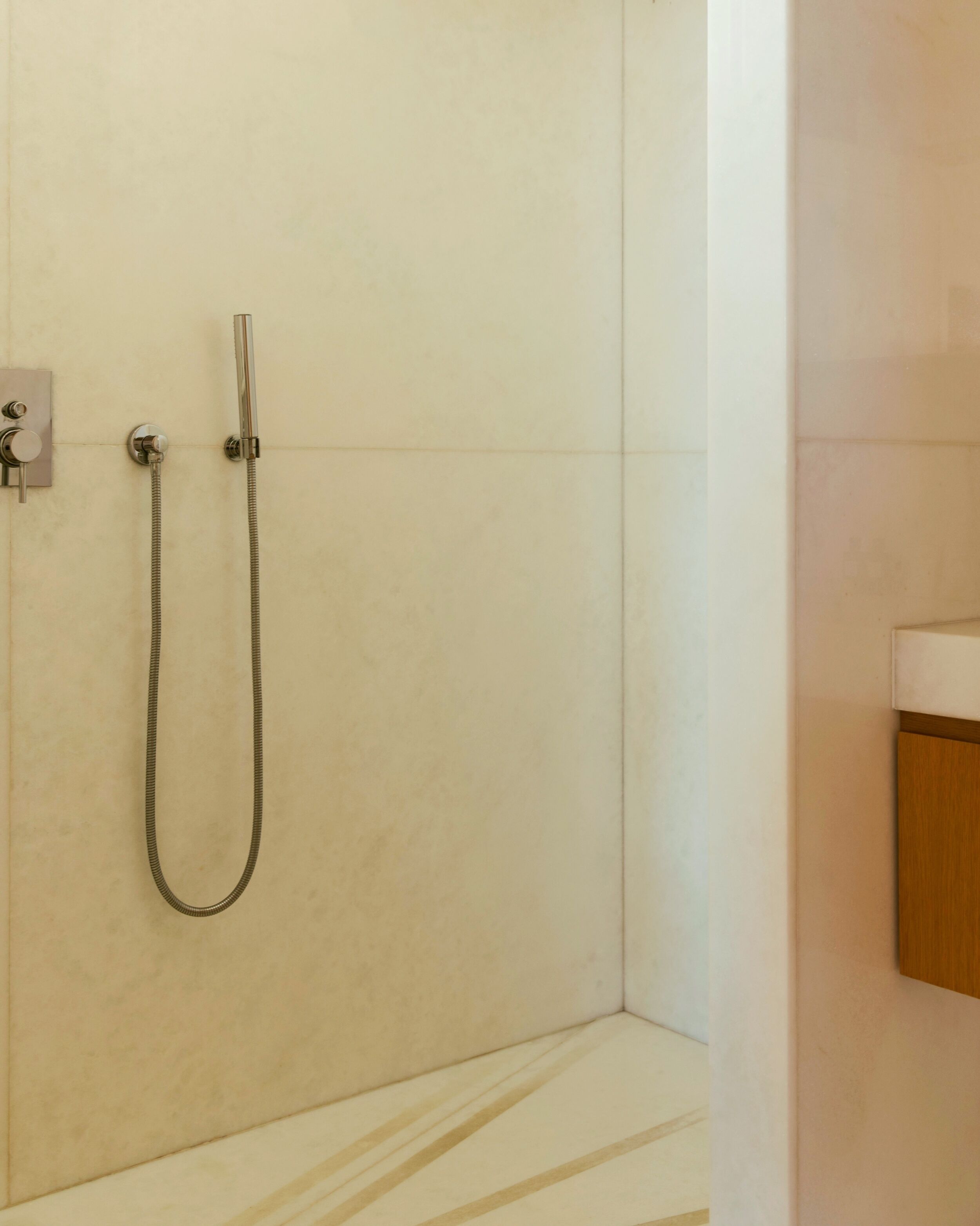 A shower area with a handheld showerhead and a wall-mounted faucet.