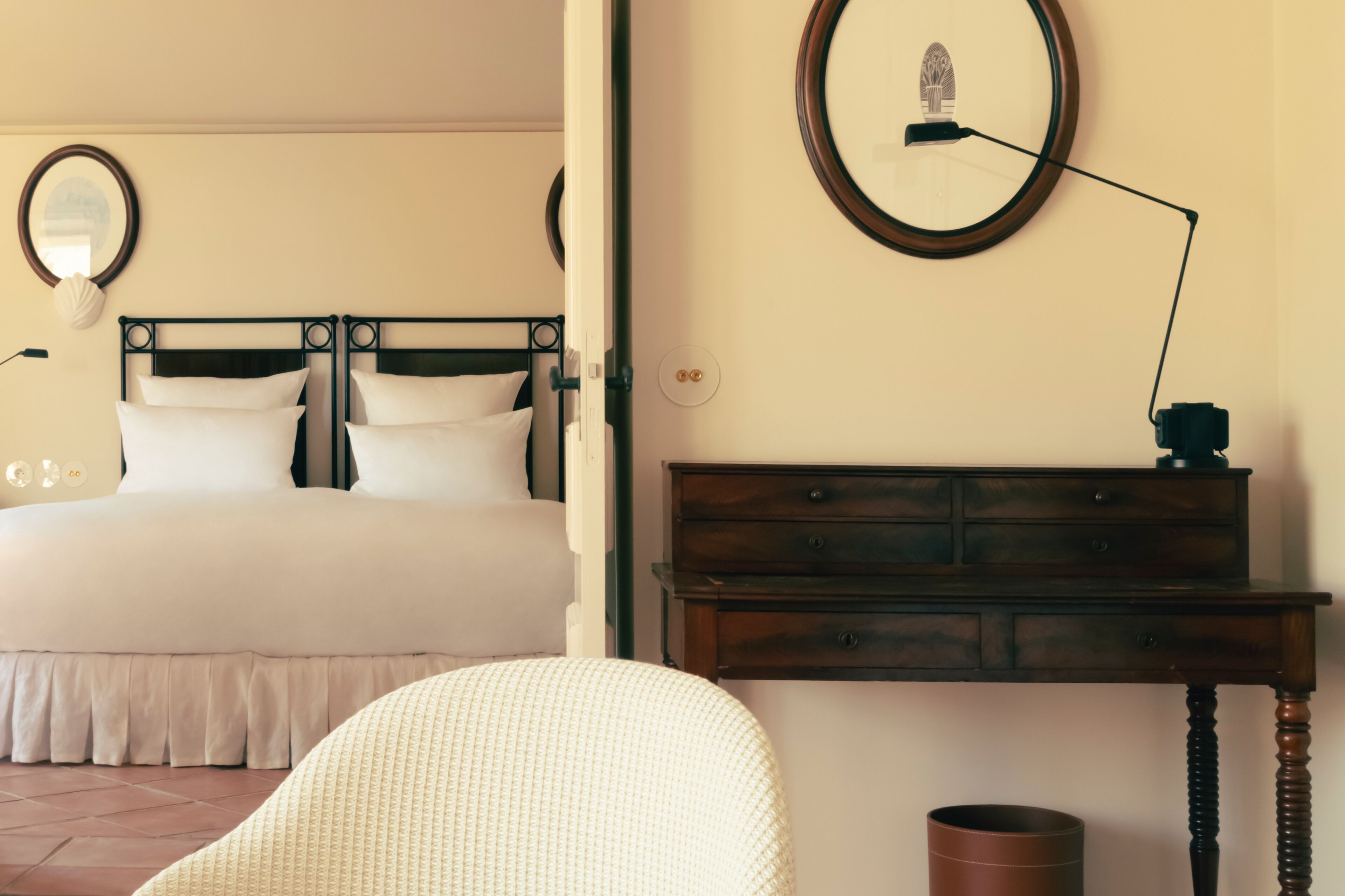 Un dormitorio con cama, mesita de noche, lámpara y espejo en la pared.