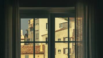A view through a window with multiple panes, revealing buildings with traditional architecture and a clear sky.