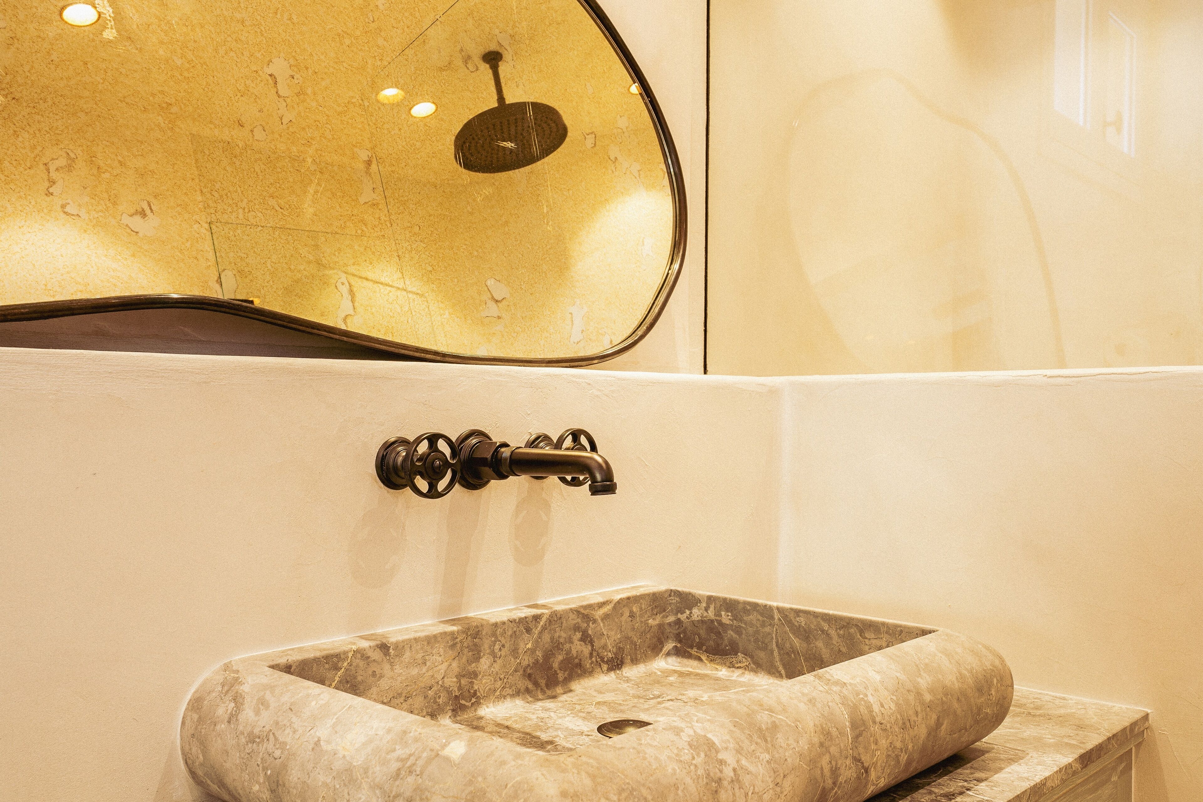 A bathroom with a marble sink, a wall-mounted mirror, and a light fixture.