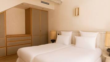 A bedroom with a large bed, wooden wardrobe, and two bedside lamps.