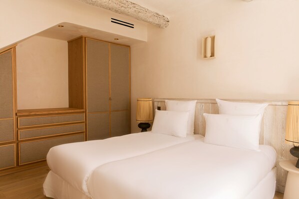 A bedroom with a large bed, wooden wardrobe, and two bedside lamps. - Hôtel La Ponche (Saint-Tropez)