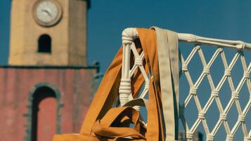 A wicker chair with a brown bag and a white cushion, set against a clear sky.