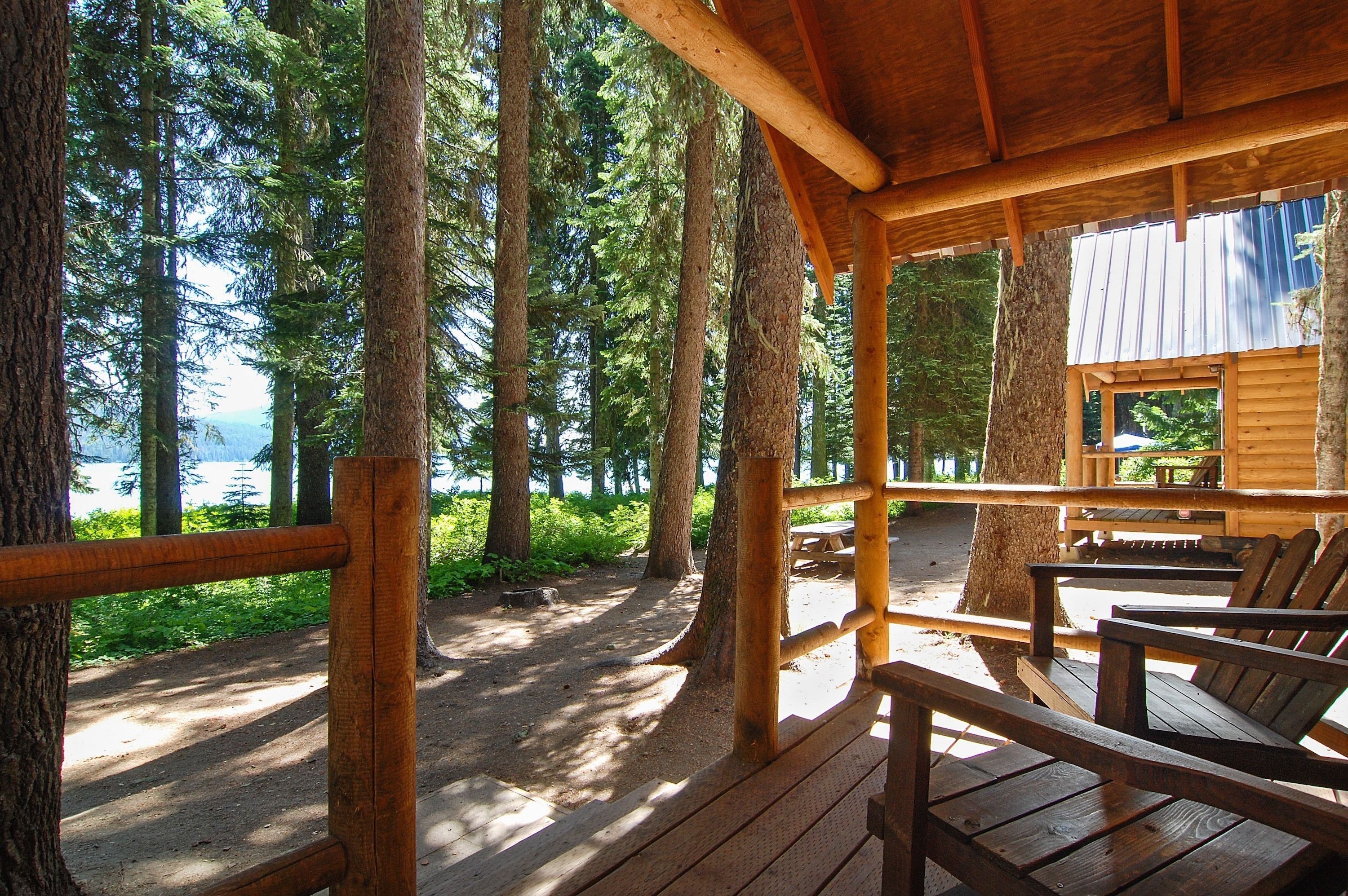 Une terrasse en bois, dotée de bancs, qui offre une vue sur une zone boisée et un plan d’eau.