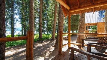 Une terrasse en bois, dotée de bancs, qui offre une vue sur une zone boisée et un plan d’eau.