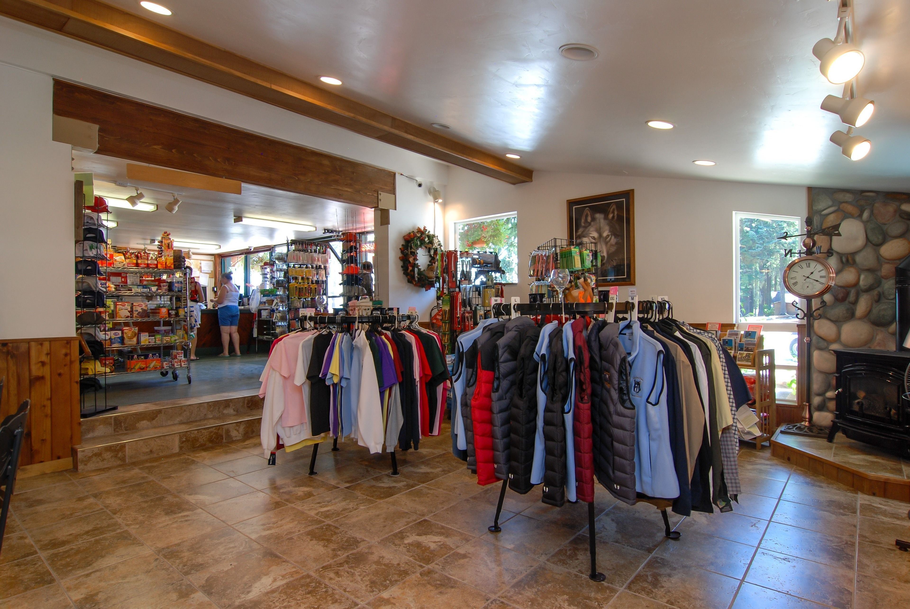 A clothing store with racks of jackets and coats, a fireplace, and a stone wall.