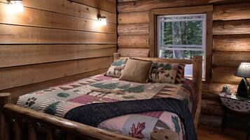 Une pièce de cabane en bois comprenant un lit, une fenêtre et une lampe sur une table d’appoint.