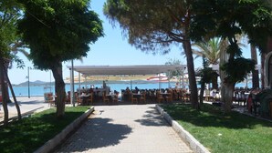An outdoor dining area with tables and chairs, a covered seating area, and a view of the sea. - Doruk Hotel (Ayvalik)