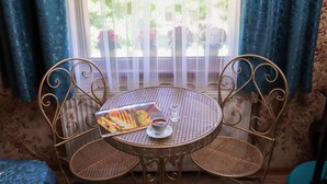 A round metal table with a woven chair, a menu, and a glass of water. - Doruk Hotel (Ayvalik)