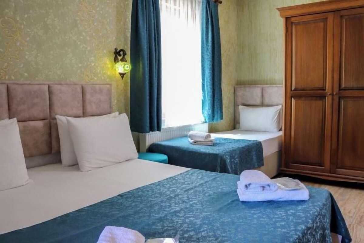 Una habitación de hotel con dos camas, un armario y una mesita de noche con lámpara.