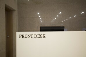 Un área de recepción con un letrero que dice “FRONT DESK” y un monitor Samsung.