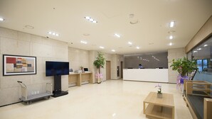 A modern reception area with a flat-screen TV, a reception desk, and a seating area with a coffee table. - Best Western Haeundae Hotel (Busan)