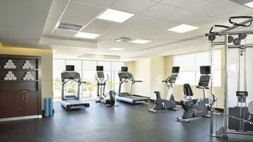 Un gimnasio con cintas de correr, máquinas elípticas y equipamiento de pesas.