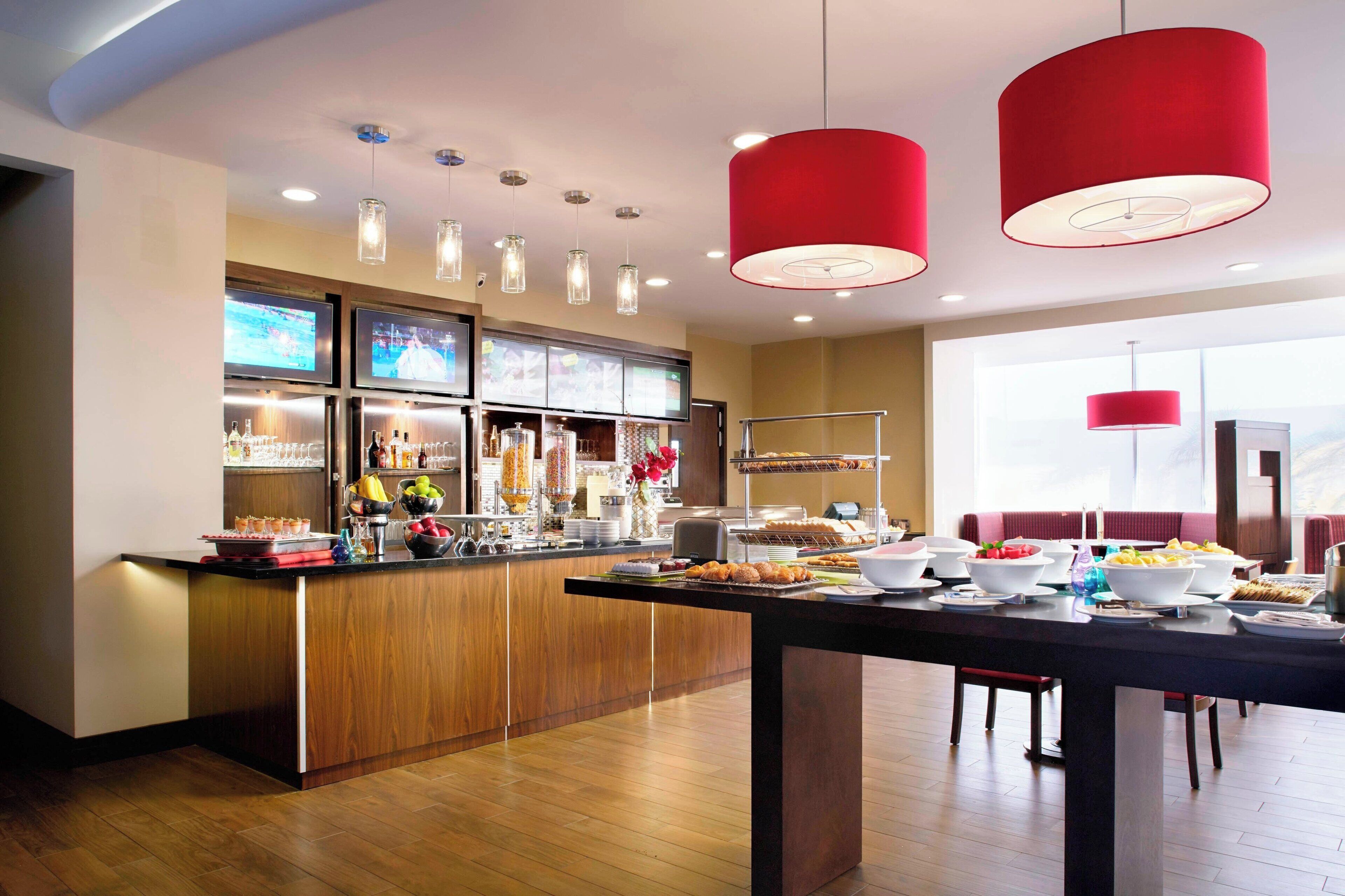 Cocina moderna con armarios de madera, una isla central con alimentos y un comedor con mesa y sillas.