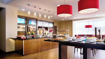 Cocina moderna con armarios de madera, una isla central con alimentos y un comedor con mesa y sillas.