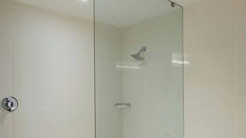 Un baño moderno con cabina de ducha de vidrio, bañera de hidromasaje y pasamanos para facilitar el acceso.