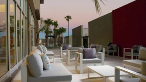 Un espace extérieur aménagé avec des meubles modernes, des palmiers et une vue sur le paysage urbain.