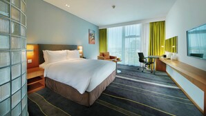 A hotel room with a large bed, a desk, a chair, and a TV.