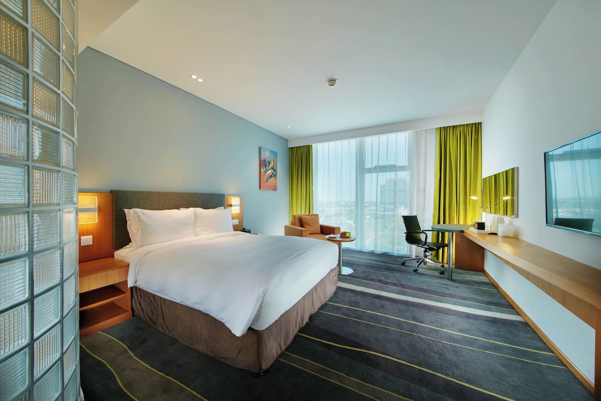 A hotel room with a large bed, a desk, a chair, and a TV.