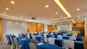 A conference room with multiple tables, chairs, and a projector screen.