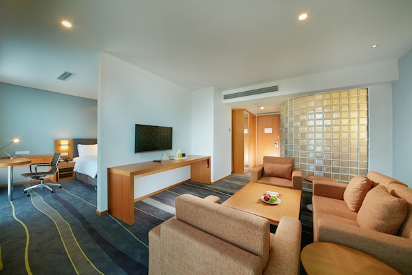 A modern hotel room with a flat-screen TV, a desk with a chair, a sofa set, and a large window with a view. - Holiday Inn Express Handan East by IHG (Handan)