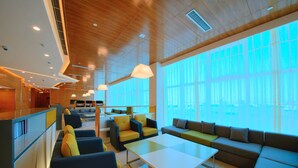 A modern interior with seating areas, a coffee table, and large windows allowing natural light.