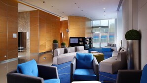A modern lobby with seating areas, a television, and a reception desk.