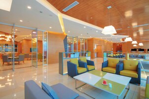 Un moderno vestíbulo de hotel con divisiones de vidrio, zonas de estar y una recepción.
