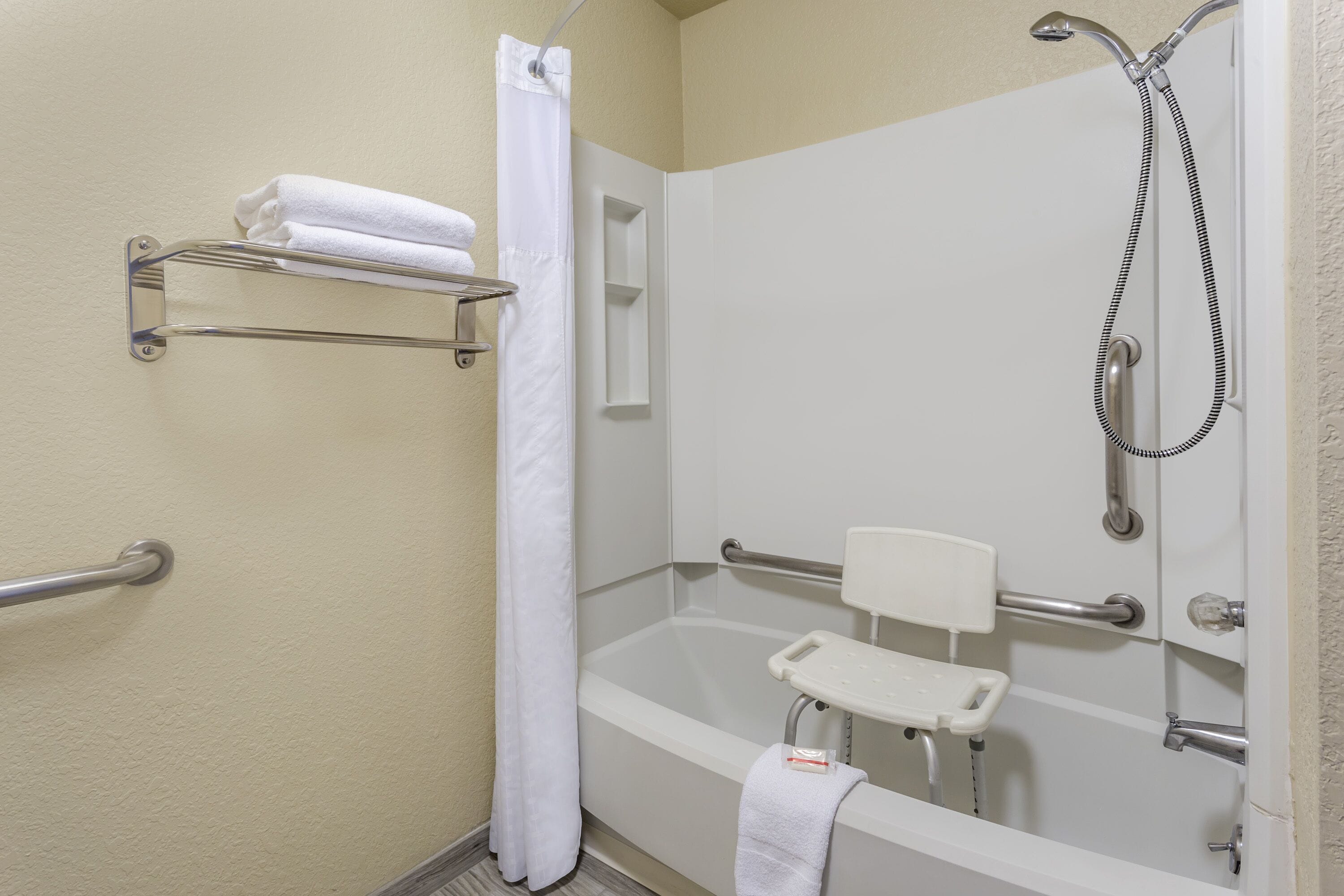 Une salle de bain équipée d’une baignoire, d’une douche et de barres d’appui.