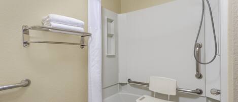 Une salle de bain équipée d’une baignoire, d’une douche et de barres d’appui.