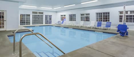 Piscina com água azul cristalina, uma escada e várias espreguiçadeiras.